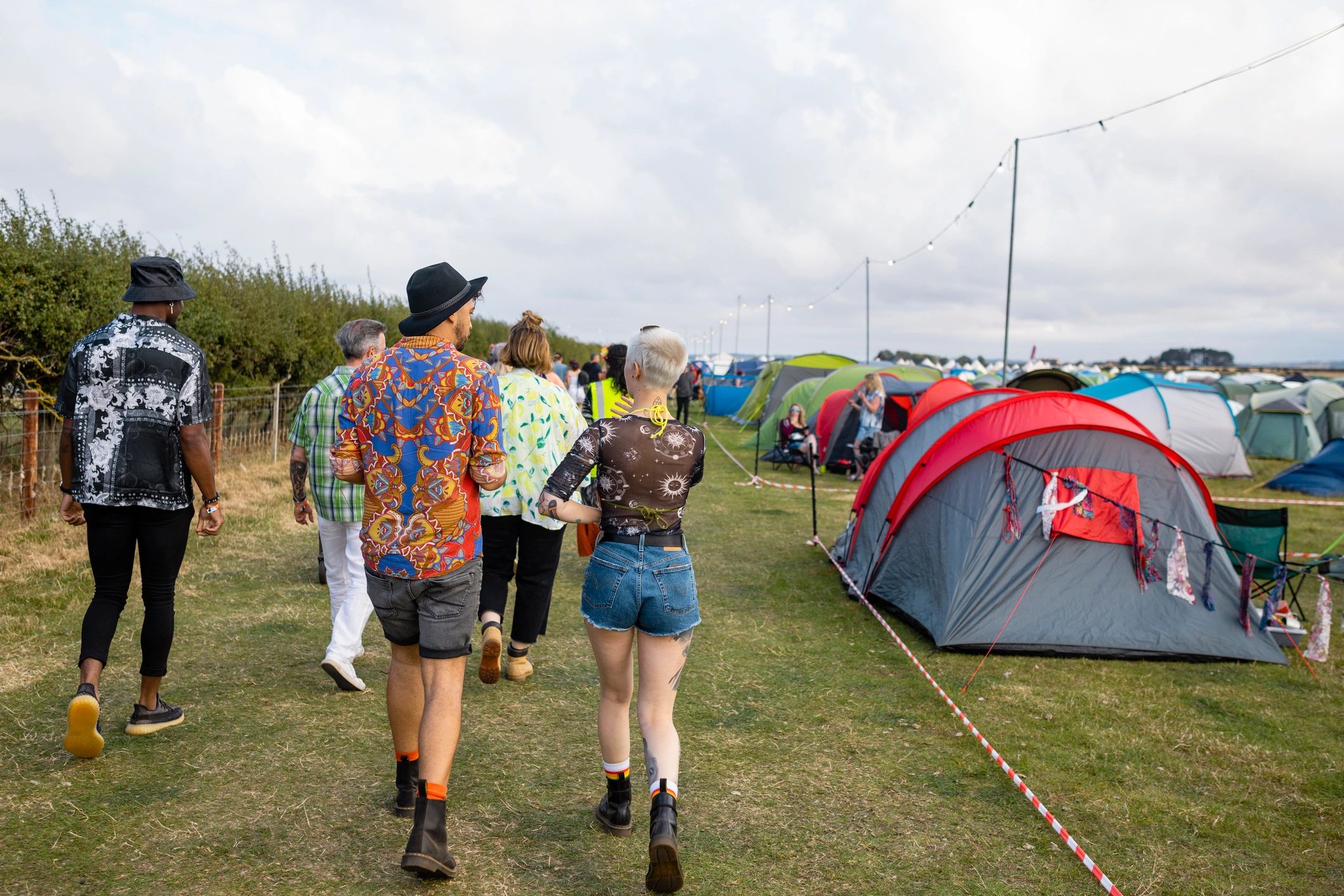 Large outdoor event crowd walking near tented festival grounds